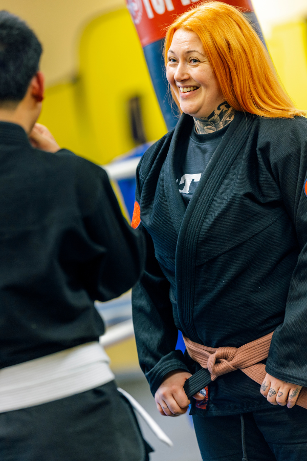 Gettogymi-lähiösalin työntekijä juttelee nauraen selin kameraan olevan nuoren kanssa.